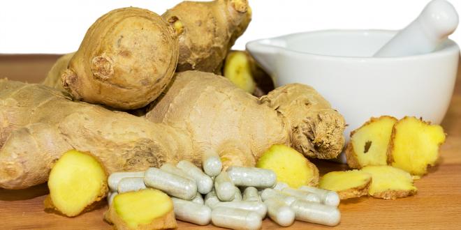 Ginger root accompanied by a motor and pestal with supplements capsules.