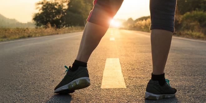 a woman stretching getting ready to run down a long flat stretch of road